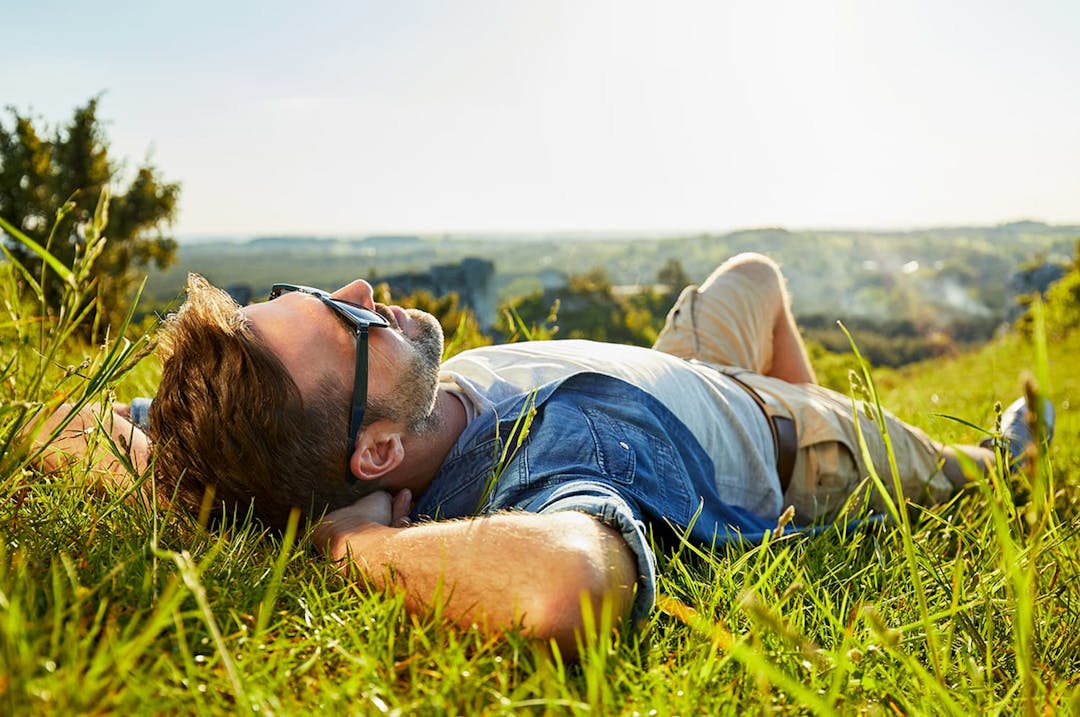 Man laying on grass, enjoying some sunshine